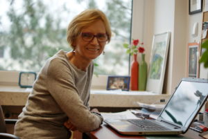 Zdjęcie przedstawia portret profesor Anny Jakubowskiej, siedzącej przy biurku , 